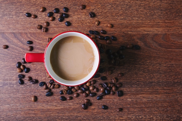 Café en una taza de café rojo sobre una mesa de madera