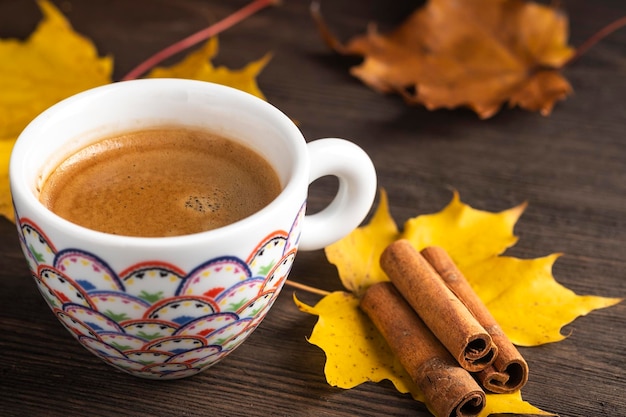 Café en una taza cerca de las hojas de otoño