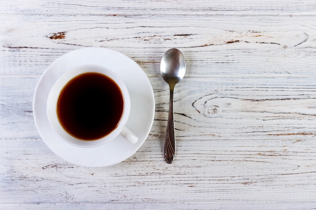 Café en una taza con una cuchara sobre un fondo blanco