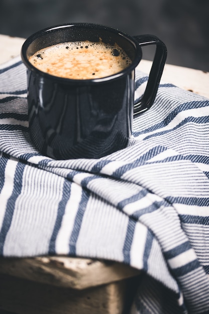 Un café en una taza oscura para acampar.