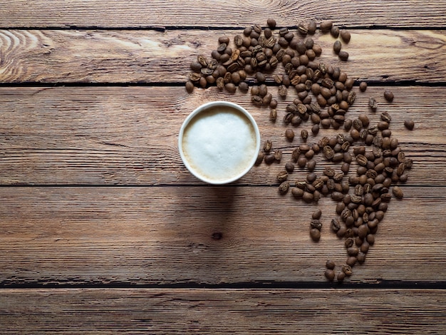 El café en una taza de papel está sobre la mesa marrón.