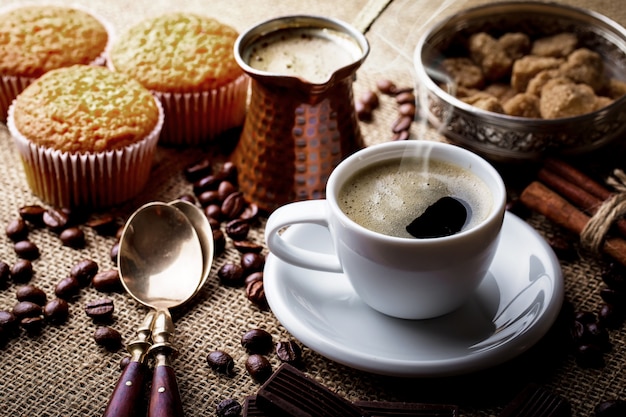 Café en una taza y platillo con granos de café.