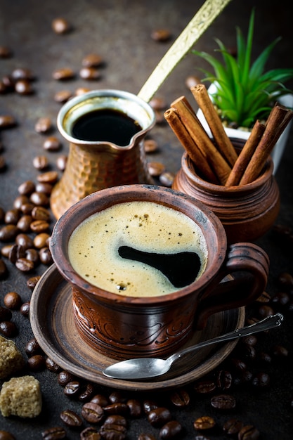 Café en una taza y platillo sobre un fondo negro