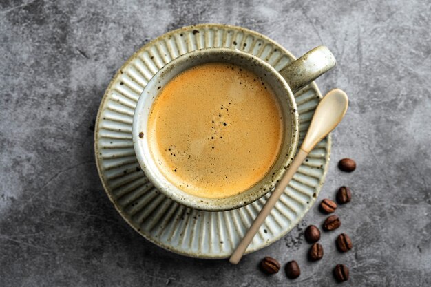 Café en una taza en un plato sobre una superficie gris