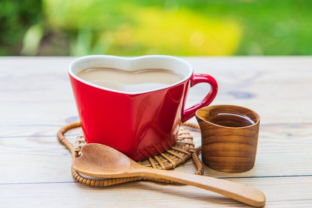 Café en la taza roja y pastel de chocolate para el desayuno en el jardín.