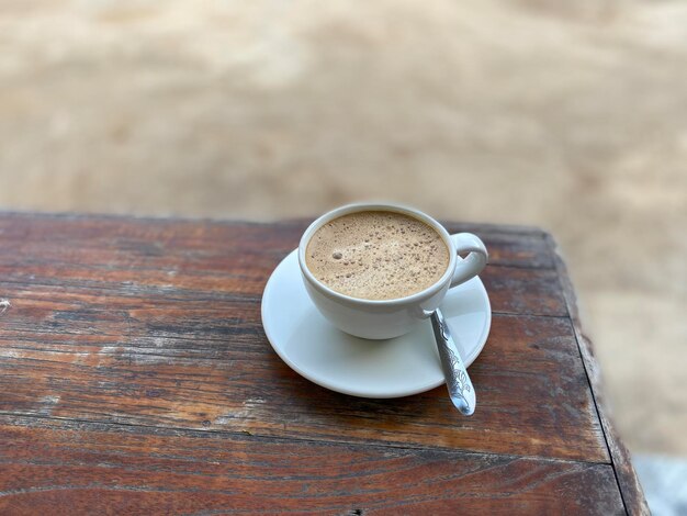 Café en una taza roja sobre una mesa de madera en un café con fondo de iluminación