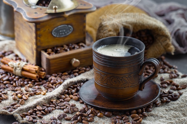 Café en una taza sobre un fondo de granos de café, sobre un fondo antiguo