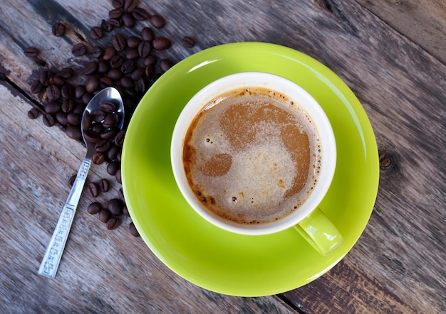 Café en taza verde sobre fondo de mesa de madera vieja, vista superior