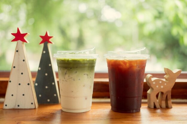 café y té verde en vasos de plástico en una mesa de madera vintage en una cafetería