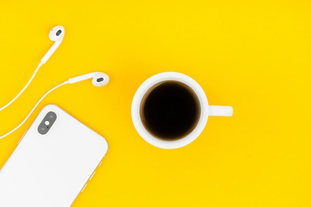 Café, teléfono y auriculares en el fondo amarillo.