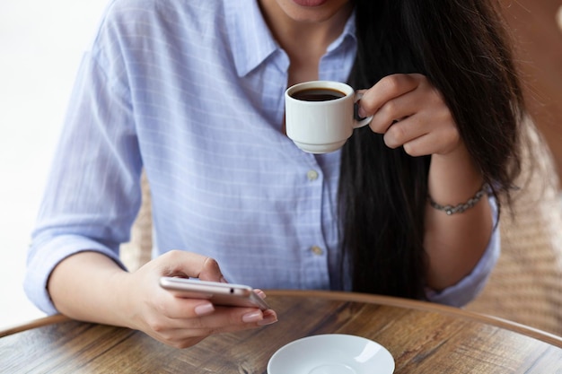 Café y teléfono de mano de mujer