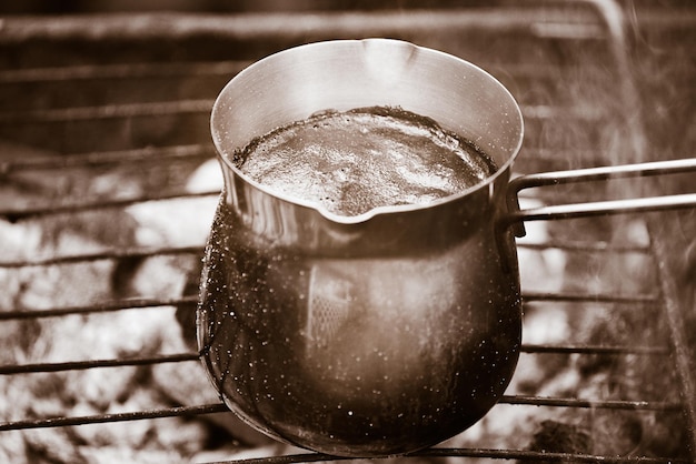 Café torrado natural é preparado em um turco de metal sobre fogo Café quente com espuma