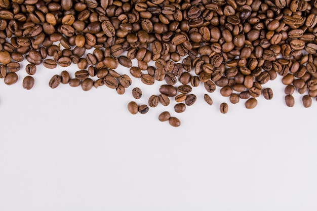 Un café tostado en grano espolvoreado sobre fondo blanco.