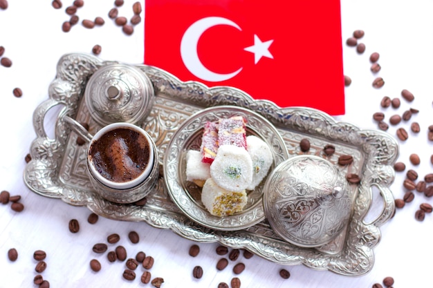 Café turco en una bandeja de plata tradicional con dulces turcos y la bandera roja de Turquía