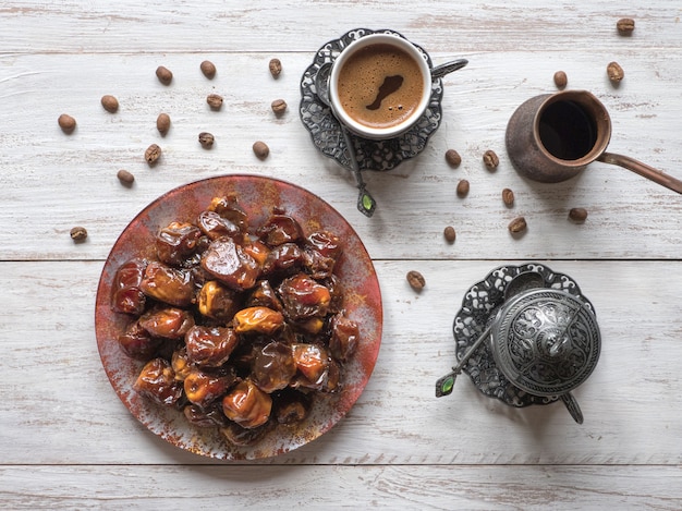 Café turco con fechas y cardamomo en la mesa de madera.