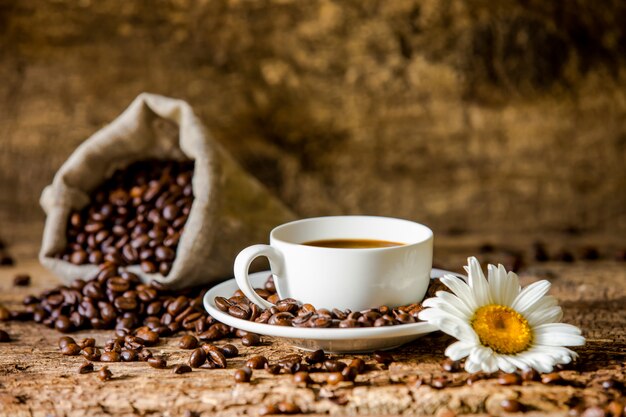 Café. Uma xícara de café quente e grãos de café torrados na madeira