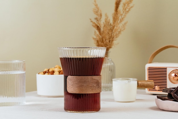 Café en un vaso transparente sobre la mesa leche en una jarra de leche chocolate en un plato