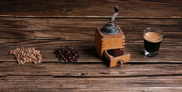 Café verde, tostado, molido con el molinillo y espresso en una mesa de madera