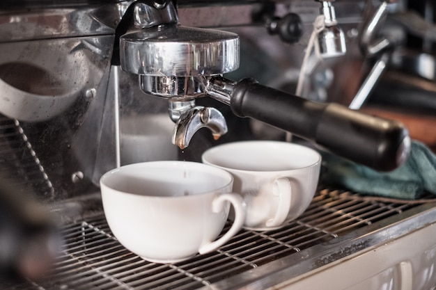 Cafeteira fazendo café em gotas em duas xícaras