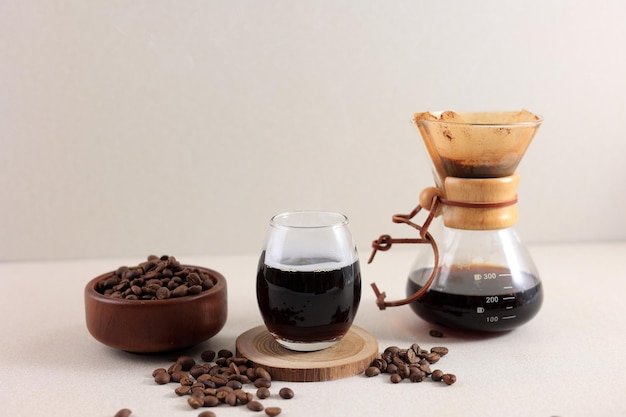 Cafetera Chemex de vidrio con saboroso café goteante y frijoles en la mesa de crema