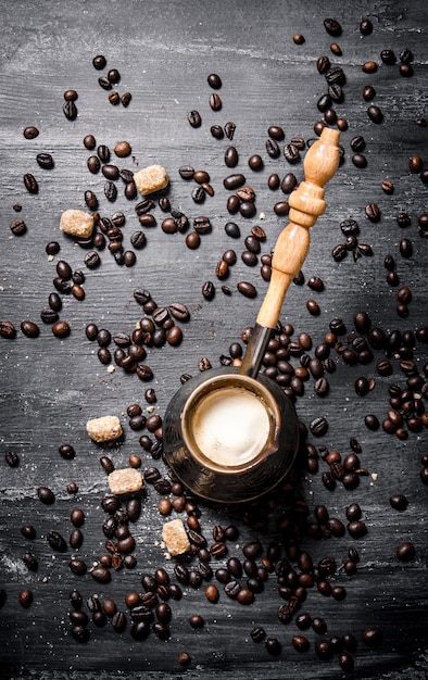 Cafetera fresca con azúcar de caña y granos tostados. En una pizarra negra.