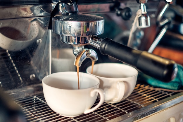 Cafetera haciendo café que fluye en taza