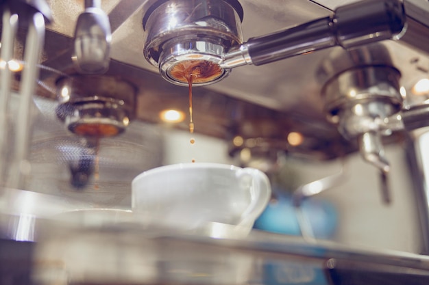 Cafetera profesional con taza de porcelana en cafetería.