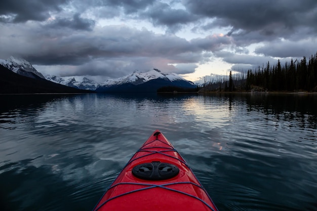 Caiaque em um lago glaciar tranquilo e calmo durante um pôr do sol nublado vibrante