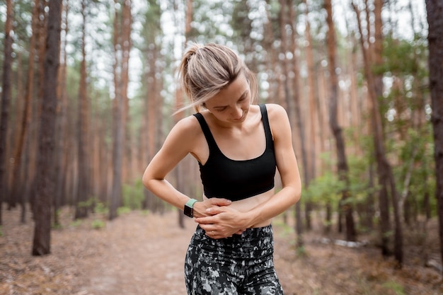 Cãibras laterais do corredor da mulher do ponto lateral após a execução. mulher movimentando-se com dor de estômago depois de correr para fora do trabalho. atleta feminina. conceito de esporte, saúde e pessoas.