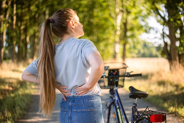 Cãibras nas costas depois de andar de bicicleta garota em jeans