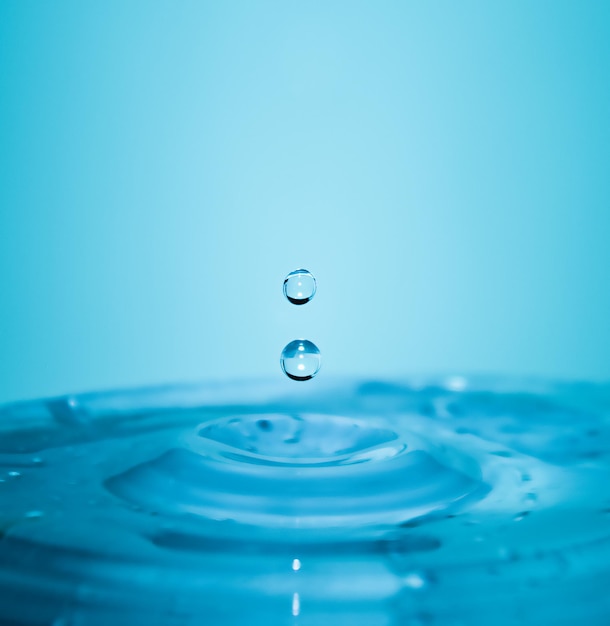 Caída de gotas de agua azul pura en macro