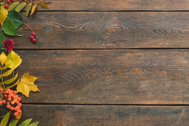 Caída de hojas de otoño se mezclan en la pared de madera rústica
