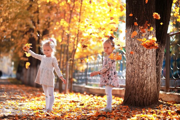 Caída de hojas en el parque. Niños a pasear por el parque de otoño. Familia. Otoño. Felicidad.