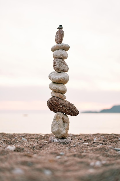 Foto cairn se encuentra en la orilla del mar en la puesta de sol rosa