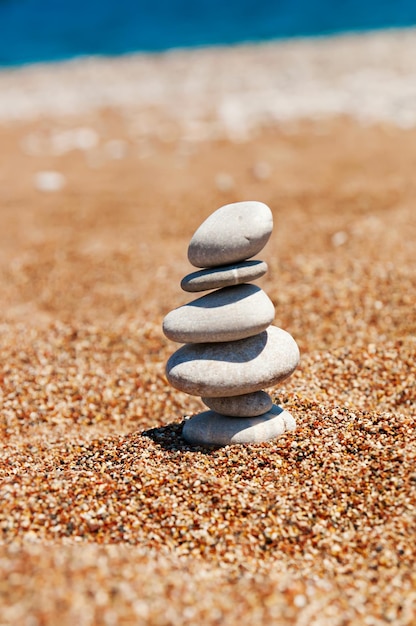 Cairn (pilha de pedras) na areia da praia perto do conceito de mar, harmonia e estabilidade