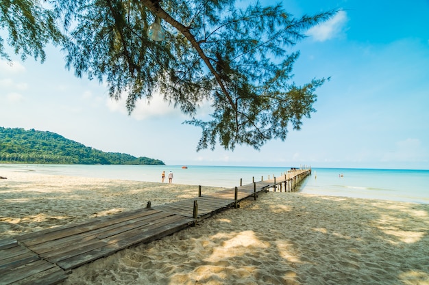 Cais de madeira ou ponte com praia tropical e mar na ilha paradisíaca