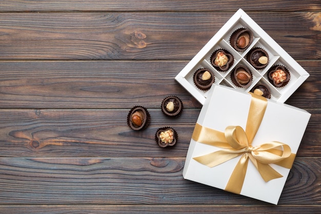 Caixa branca com bombons de chocolate e vista superior de fita dourada com espaço de cópia