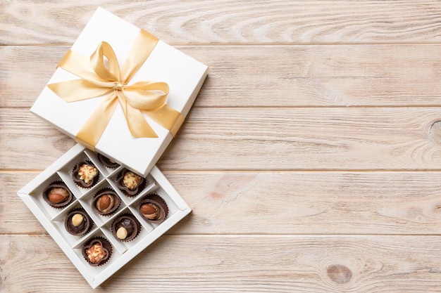 Caixa branca com bombons de chocolate e vista superior de fita dourada com espaço de cópia