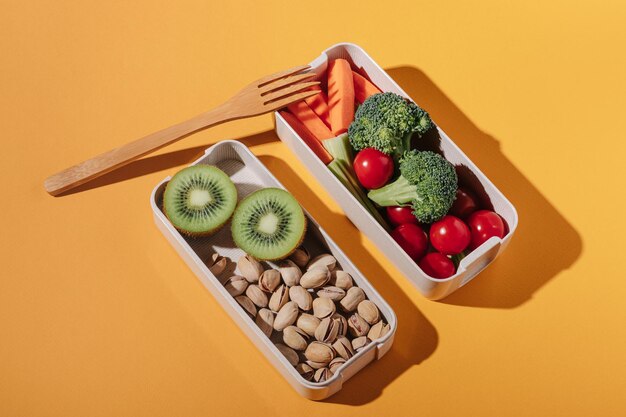 Caixa de almoço com frutas e nozes de legumes frescos em fundo amarelo
