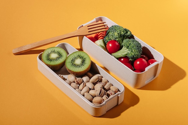 Caixa de almoço com frutas e nozes de legumes frescos em fundo amarelo