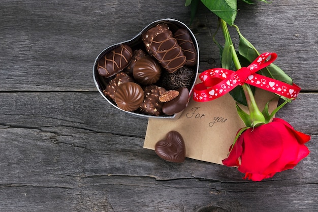 Caixa de chocolates, rosa vermelha em um fundo escuro