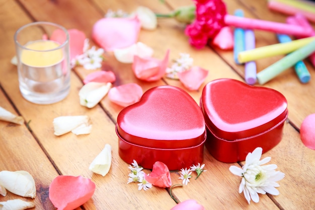 Caixa de coração vermelho com pétalas de flores decorativas na mesa de madeira. fundo para o conceito de dia dos namorados