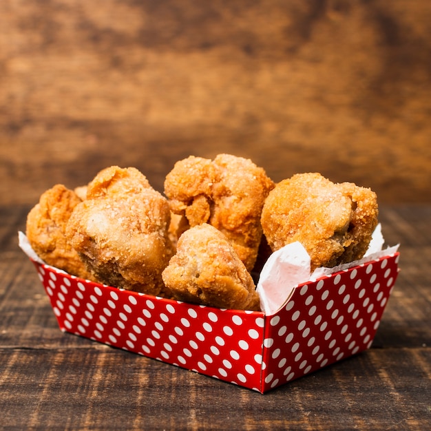 Foto caixa de frango frito na mesa de madeira