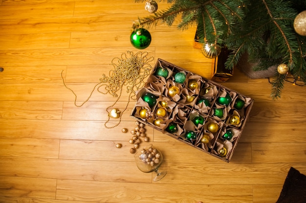 Caixa de madeira com bolas de ouro e verdes e brinquedos para a decoração, Natal e ano novo