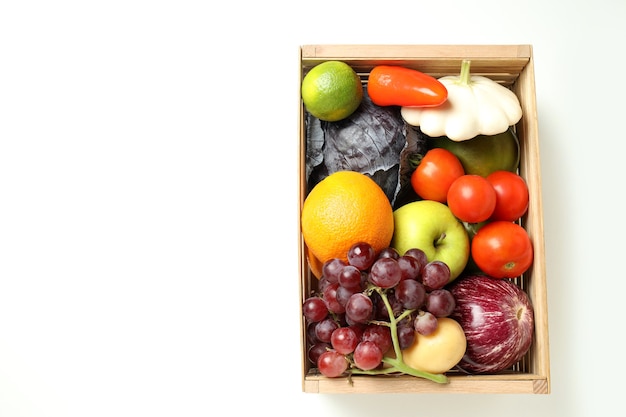 Caixa de madeira com legumes e frutas em fundo branco