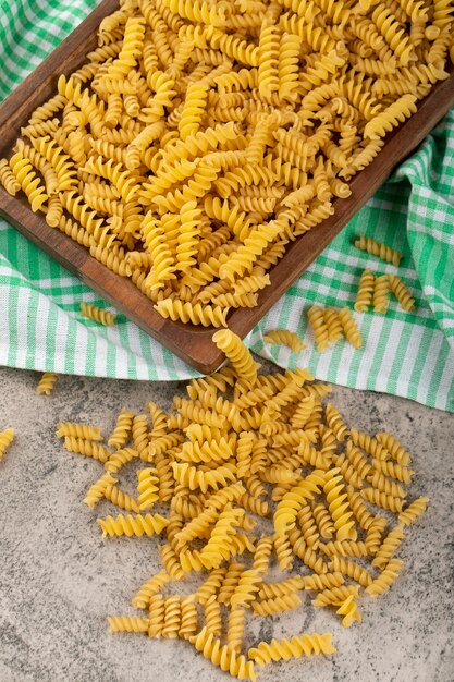 Caixa de madeira de massa fusilli crua seca na mesa de pedra.