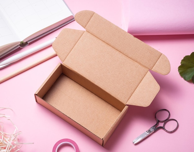 Caixa de papelão aberta em fundo rosa decorada com flores vermelhas