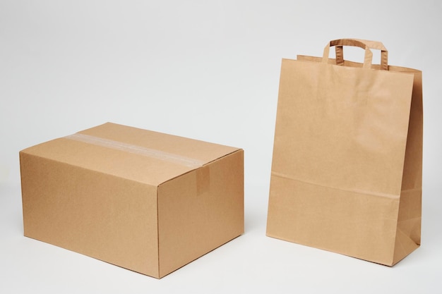 Caixa de papelão e saco de papel isolado no fundo branco com espaço de cópia Conceito de serviço de entrega e envio Saco de compras de papel e caixa de pacote de encomendas closeup