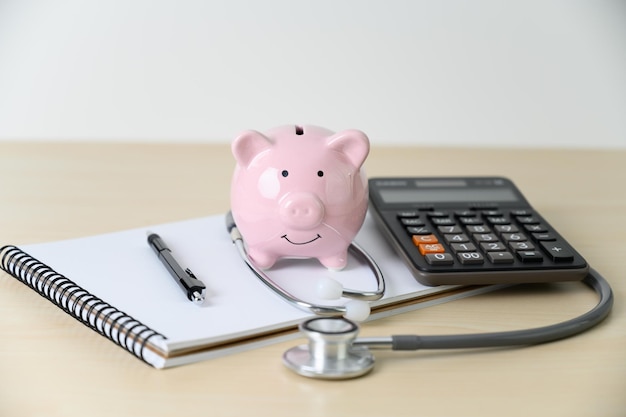 Foto caixa de porcos com estetoscópio e calculadora na mesa da clínica