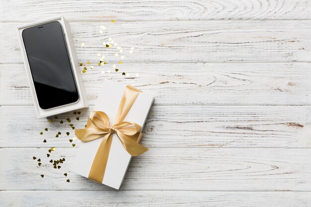 Caixa de presente aberta com fita dourada e smartphone na vista superior de fundo colorido Maquete de embalagem de caixa aberta em branco Modelo para sua maquete de marca de design